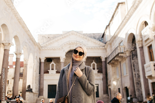 portrait of young European Muslim women with hijab and looking at the camera. She is exploring old city of Split as tourist. Diocletian's palace. 