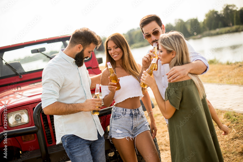 Obraz premium Group of young people drinking and having fun by car outdoor