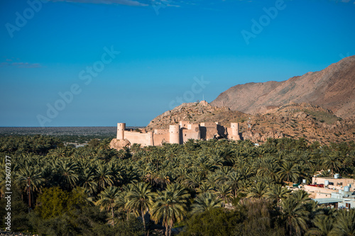 Sunset view of the Nakhal Fort surrounded by a palm grove, Oman