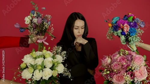 Confident bunette woman standing with crossed arms and choosing flowers photo