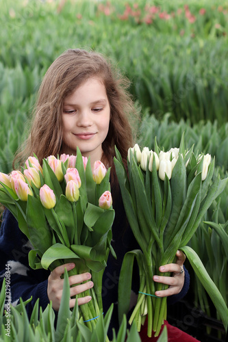Girl holding a bouquet of tulips. A florist gardener holds a bouquet of flowers while standing in a greenhouse where tulips are grown
