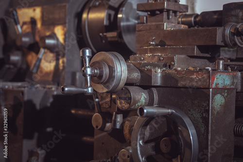 closeup of Old metallic lathe working against factory industrial interior background.