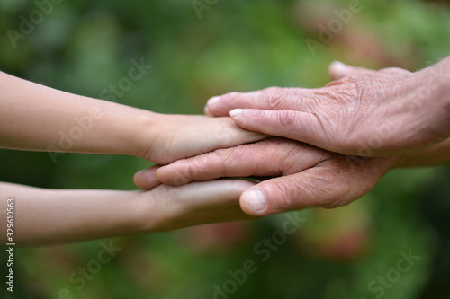 Close up granddaughter and grandmother holding hands outdoors