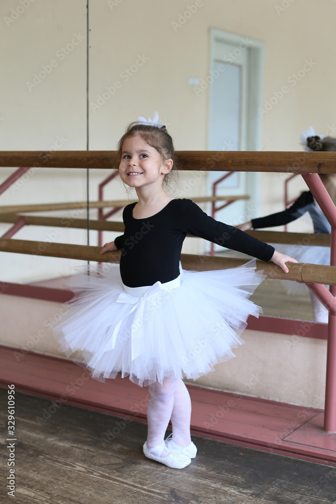Fototapeta premium vertical portrait of a smiling little ballerina at the ballet machine