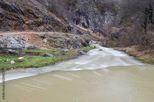 Amazing view of fast cascades of a mountain river, foreground rocks covered by colorful moss and a narow canyon photo
