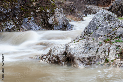 Amazing view of fast cascades of a mountain river, foreground rocks covered by colorful moss and a narow canyon photo