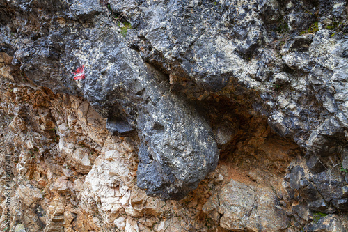 Red hiking track marking on a black, wet, erroded rocky cliff photo