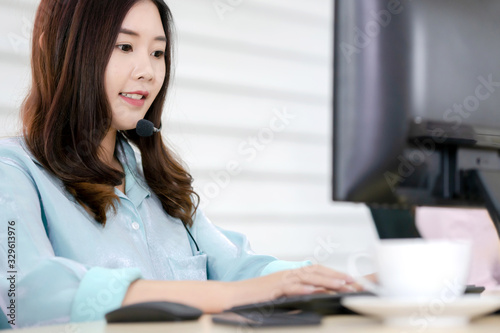 Call center office. Beautiful woman using computer and headset for consulting clients online.