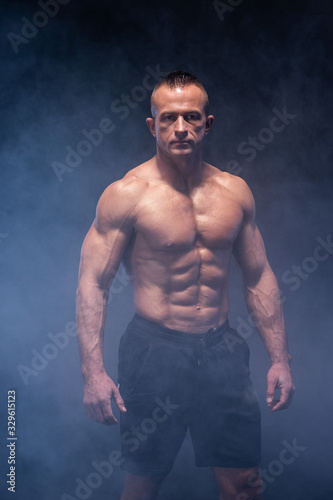 Muscular man isolated on the black background. Strong male naked torso abs