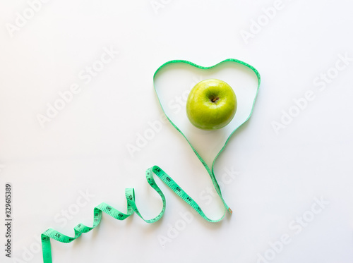 Conceptual images of healthy food lose weight and not make you fat, healthy, with green apples placed in the waist measuring a heart shaped on the white background and copy space.