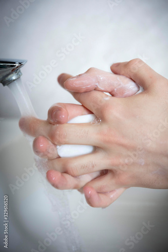 Detail of Caucasian hands - washing with a soap bar under running water