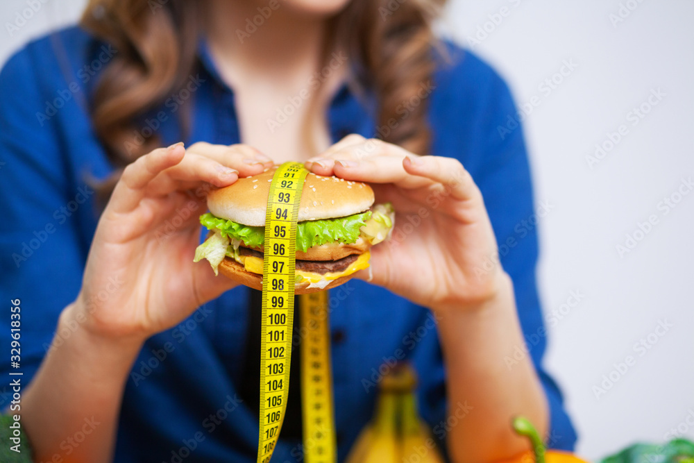 Concept of healthy eating, burger with yellow tape measure