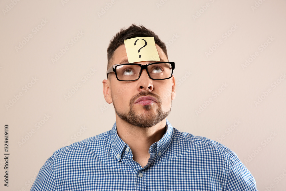 Fototapeta premium Man in eyeglasses with question mark on grey background
