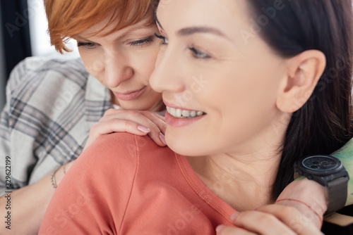 Selective focus of woman hugging smiling girlfriend at home
