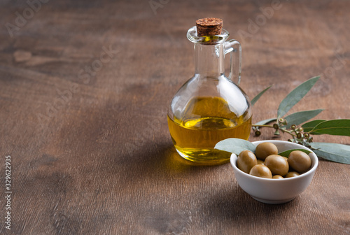 ripe natural eco friendly olives with olive oil in a bottle on a brown wooden background.