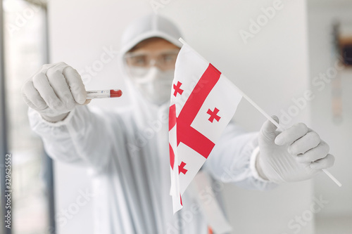 The scientist in coverall suit with a coronavirus sample and Georgian flag.