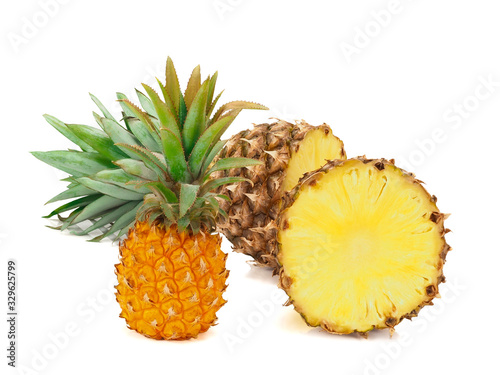 One whole baby pineapple with green leaves and two halves of pineapple isolated on a white background