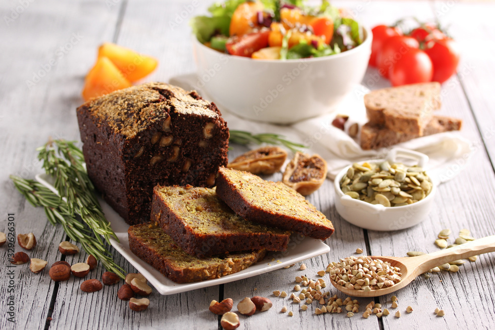 Healthy food. Sliced bread with a bowl of salad of fresh vegetables and herbs. Nuts, lettuce, seeds, figs, cereals, tomatoes on a light wooden background. Background image, copy space Healthy food. Sliced bread with a bowl of salad of fresh vegetables and herbs. Nuts, lettuce, seeds, figs, cereals, tomatoes on a light wooden background. Background image, copy space