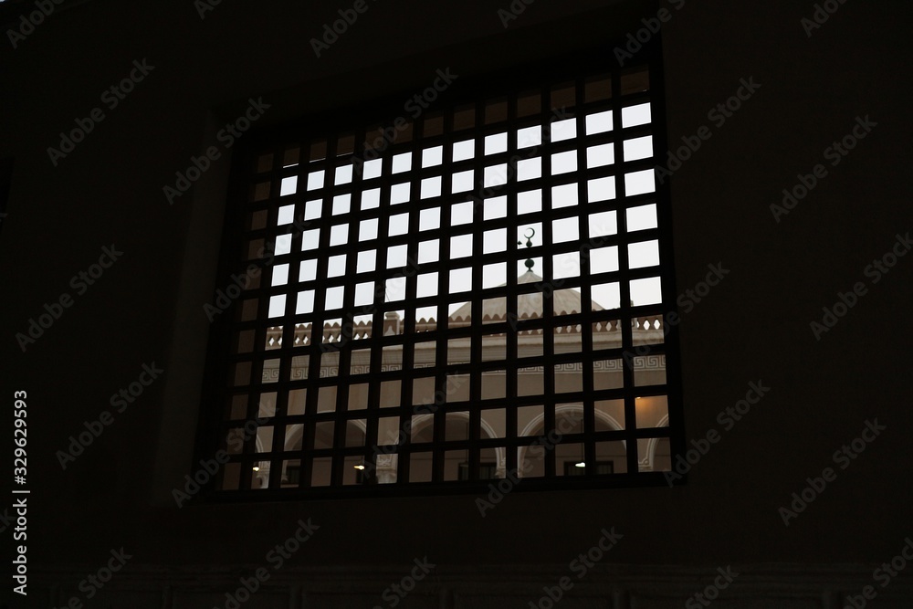 Crescent on mosque dome seen through square lattice window Crescent on mosque dome seen through square lattice window