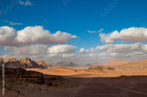 Kingdom of Jordan, Wadi Rum desert, sunny winter day scenery landscape with white puffy clouds and warm colors. Lovely travel photography. Beautiful desert could be explored on safari. Colorful image