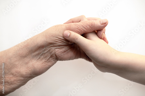 Human hands wrinkled adult senior and child holding each other. Bonding a great-grandmother and grandson. Love the emotion.