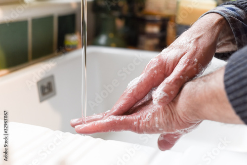 Wash hands with soap to prevent spread of germs Male hands washing in the sink