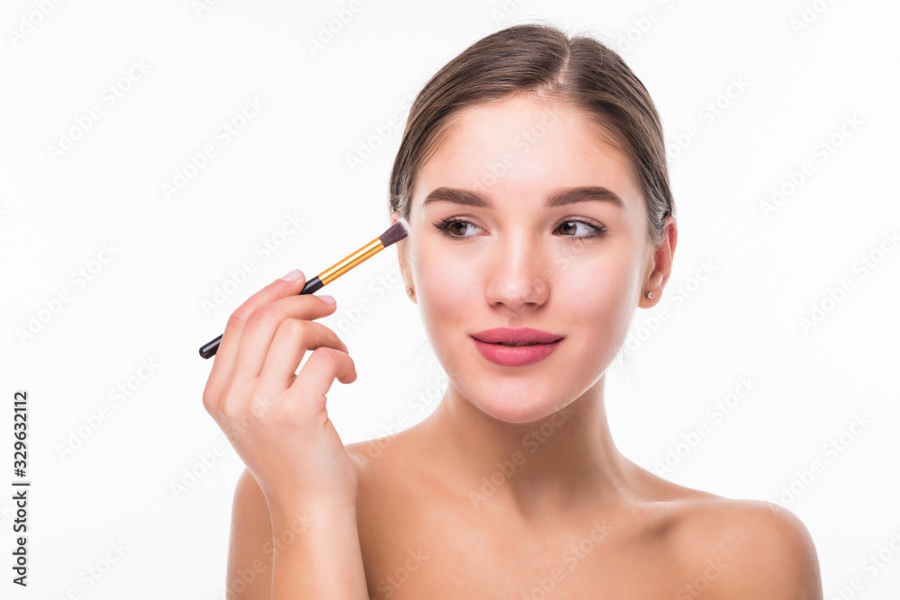 Closeup portrait of a woman applying dry cosmetic tonal foundation on the face using makeup brush isolated on white background Closeup portrait of a woman applying dry cosmetic tonal foundation on the face using makeup brush isolated on white background