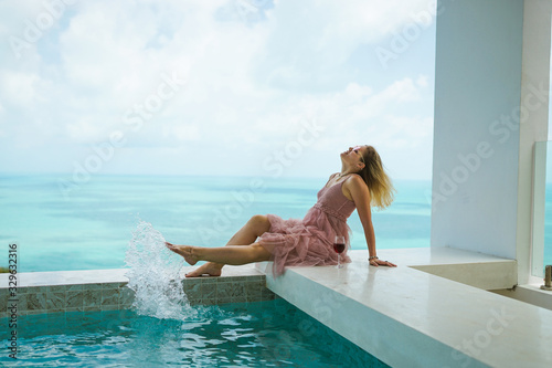 A beautiful woman is relaxing in a rich villa with a pool with luxurious views of the sea and palm trees. Portraits of the face. Nice vacation. Exotic and tropics with a girl.