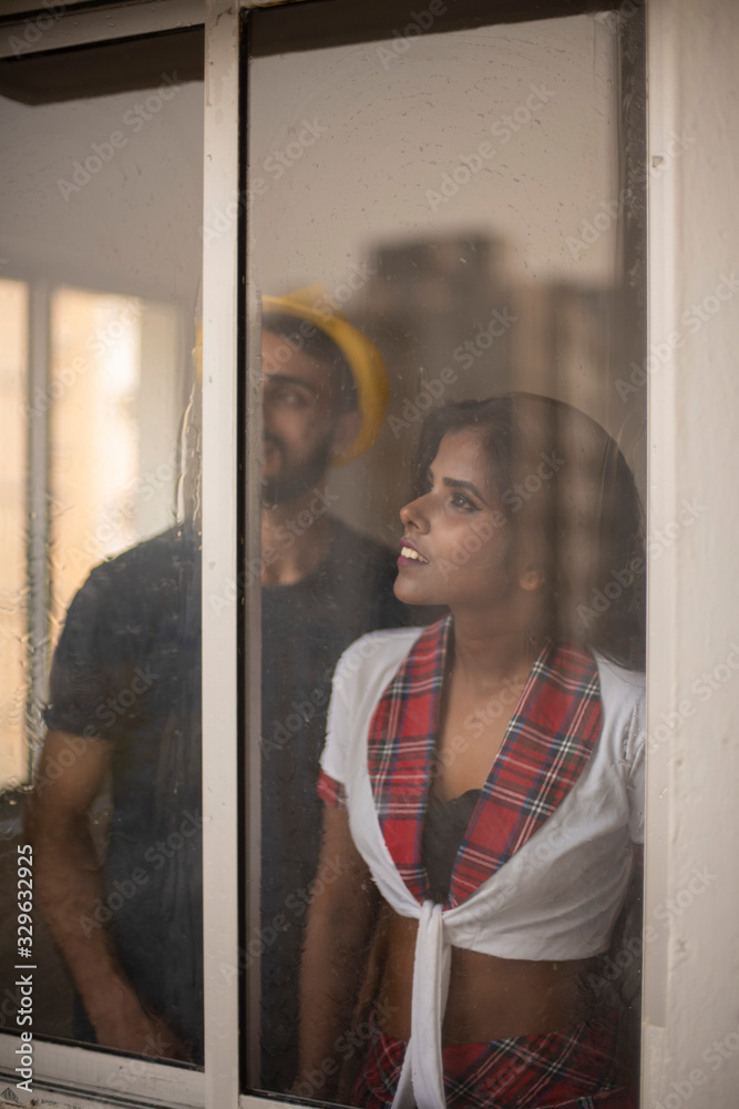 Φωτογραφία Blurred portrait of a dark skinned Indian/African girl in school uniform and a Kashmiri/European/Arabian man in casual wear and hat standing in front of closed glass window