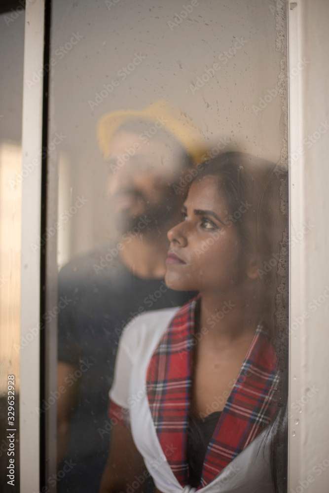Φωτογραφία Blurred portrait of a dark skinned Indian/African girl in school uniform and a Kashmiri/European/Arabian man in casual wear and hat standing in front of closed glass window