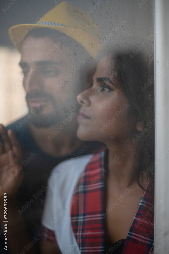 Φωτογραφία Blurred portrait of a dark skinned Indian/African girl in school uniform and a Kashmiri/European/Arabian man in casual wear and hat standing in front of closed glass window