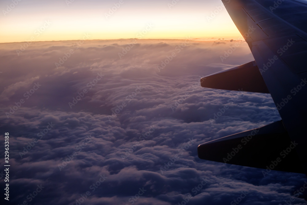 Silhouette airplane wing over the clouds at sunrise