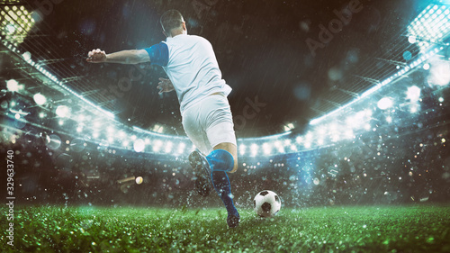 Close up of a soccer scene at night match with player in a white and blue uniform kicking the ball with power © alphaspirit