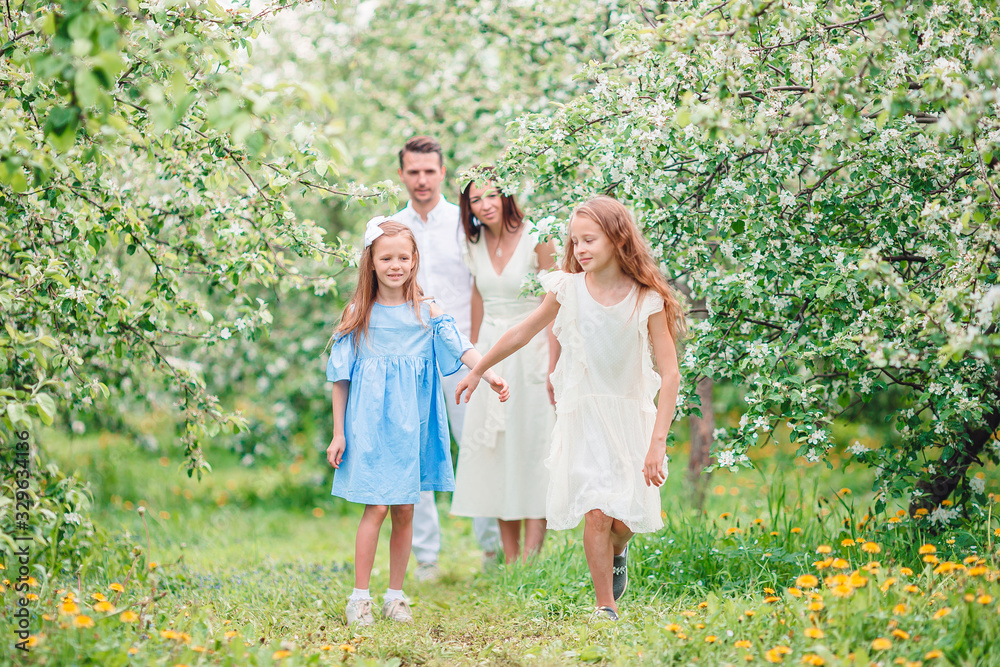 Adorable family in blooming cherry garden on beautiful spring day Adorable family in blooming cherry garden on beautiful spring day