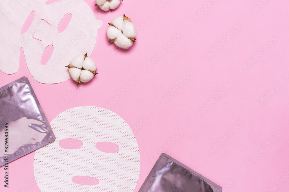 Fabric face mask, cotton flowers on pink background. Concept of natural cosmetics, face care, spa, face cream, women's beauty accessories. Flat lay top view copy space. Cosmetics mock-up
