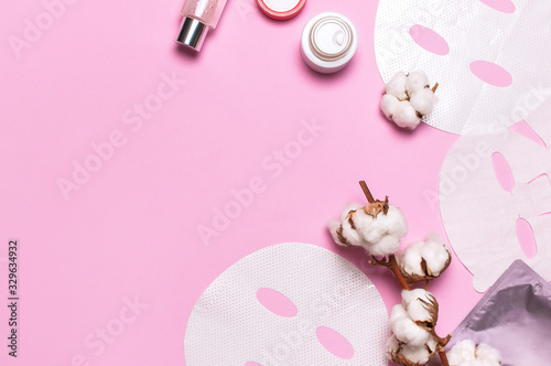 Fototapeta Naklejka Na Ścianę i Meble -  Fabric face mask, cotton flowers on pink background. Concept of natural cosmetics, face care, spa, face cream, women's beauty accessories. Flat lay top view copy space. Cosmetics mock-up