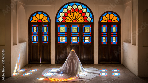 Unidentified Iranian woman in chador hijab praying inside Tabatabaei Natanzi Khaneh Historical House in Kashan, Iran photo