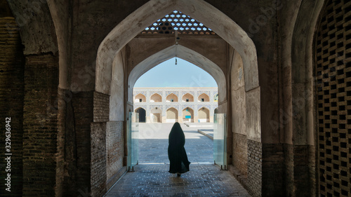 Unidentified woman in hijab walking towards the courtyard of the Great Mosque of Jameh Mosque of Isfahan, Iran © CanYalicn