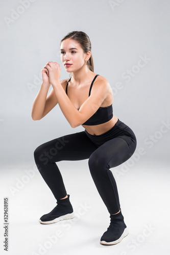 Sporty athletic woman squatting doing sit-ups in gym isolated over white background