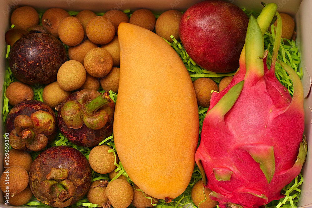 Beautiful tropical exotic fruits in the box mango, dragon fruit pitahaya, mangostin, longan, passion fruit. Summer vacation asian fresh vitamin food