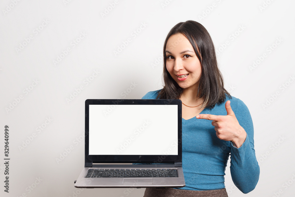 beautiful business woman smile sitting at the desk looking at camera, point finger at isolated white laptop screen beautiful business woman smile sitting at the desk looking at camera, point finger at isolated white laptop screen