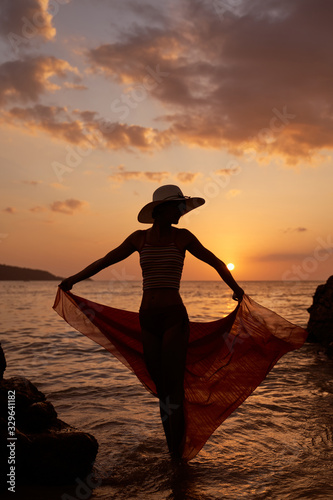 Contrast silhouette young slender woman against background of Sunny sunset  sea sandy beach. Warm evening tones. Lady walking on beach in sunset  vacation city Patong Phuket country Thailand  vertical