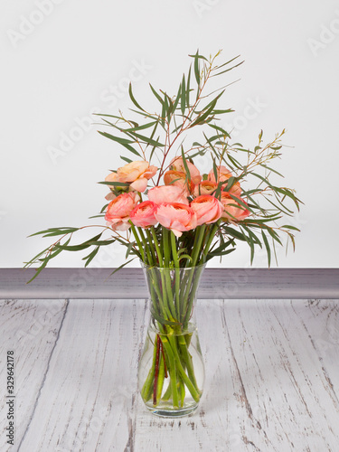 Bouquet of fresh pink ranunculus with eucalyptus in glass vase © Arra Vais