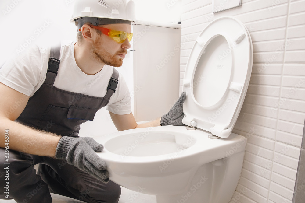Plumber installing toilet bowl in restroom, work in bathroom Photos