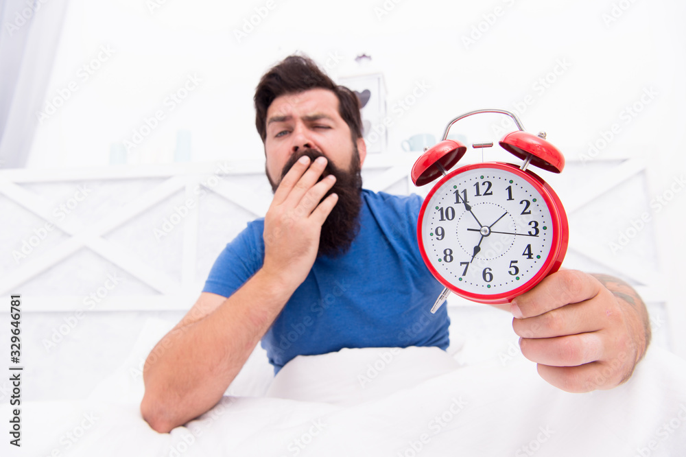 Wake up early every morning. Health benefits of rising early. Waking up early gives more time to prepare and be timely. Hipster bearded man in bed with alarm clock. Time to wake up. Healthy habits Wake up early every morning. Health benefits of rising early. Waking up early gives more time to prepare and be timely. Hipster bearded man in bed with alarm clock. Time to wake up. Healthy habits