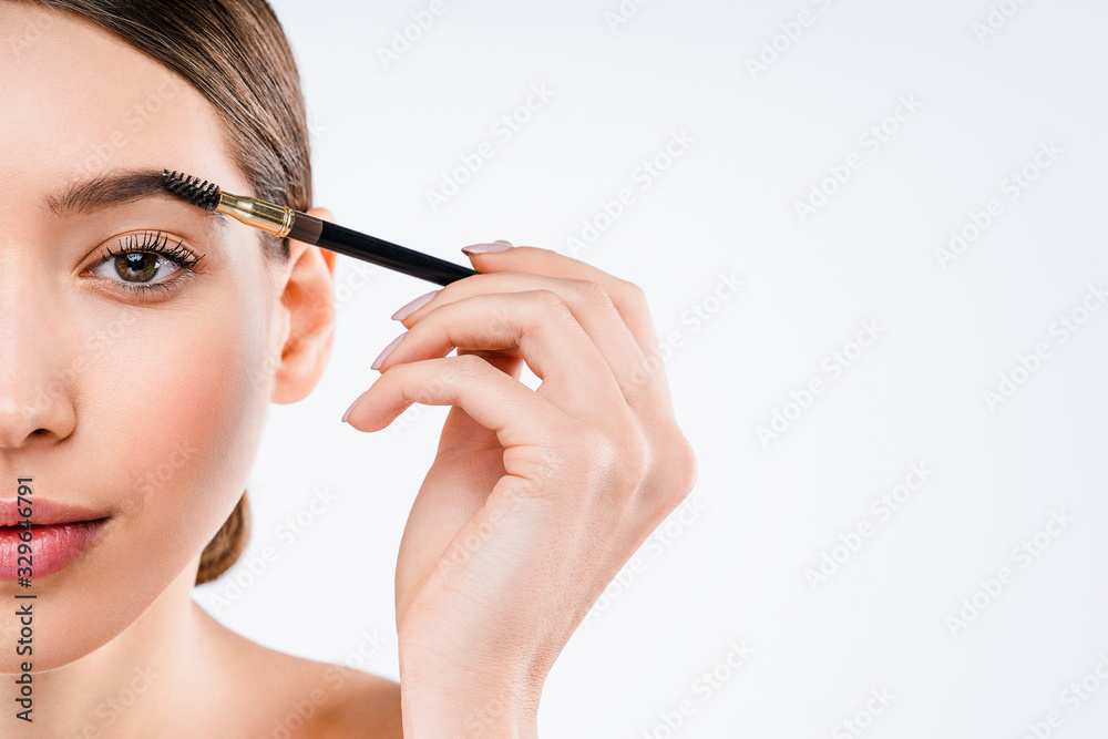 Studio shot of beautiful young woman having makeup on her eyebrow applying while standing at isolated white background Studio shot of beautiful young woman having makeup on her eyebrow applying while standing at isolated white background