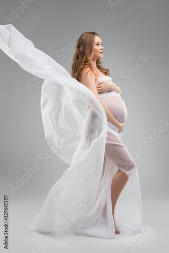 Young pregnant woman wrapped in white fabric photo