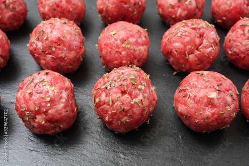 bright raw meatballs on the background of dark basalt plate