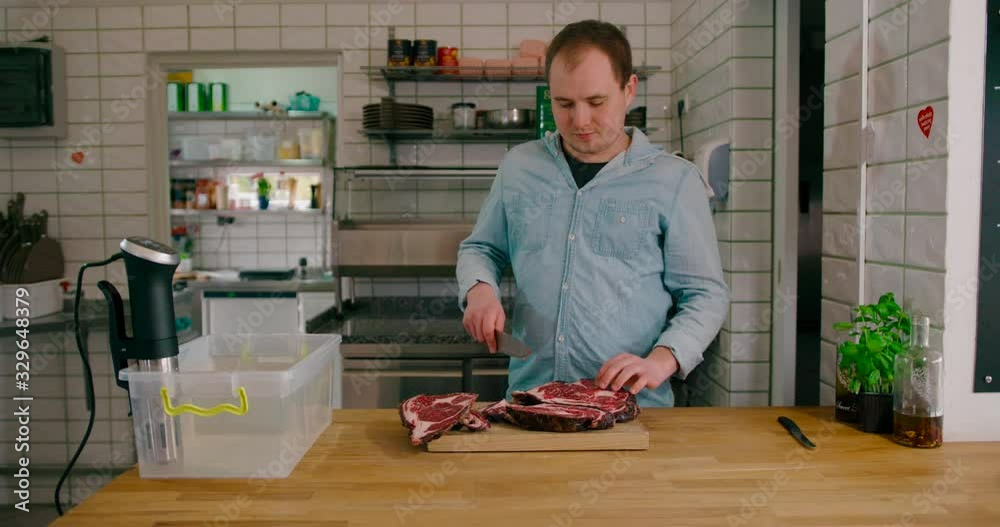 View of a man slicing the steak with ss sharp knife. next to the Sous Vide Precision Cooker. View of a man slicing the steak with ss sharp knife. next to the Sous Vide Precision Cooker.