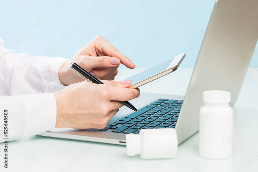 Fototapeta premium Doctor's hand uses a laptop and digital tablet on a blue background. medicine concept, modern technology